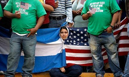 Joven salvadoreña se envuelve en las banderas de Estados Unidos y El Salvador, en una manifestación de protesta contra medidas antimigratorias. Foto AFP/Chip Somodevilla