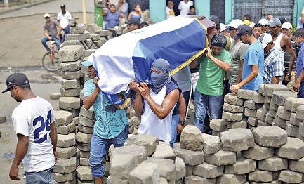 Una barricada en Masaya con manifestantes que llevan a hombros el féretro de un caído